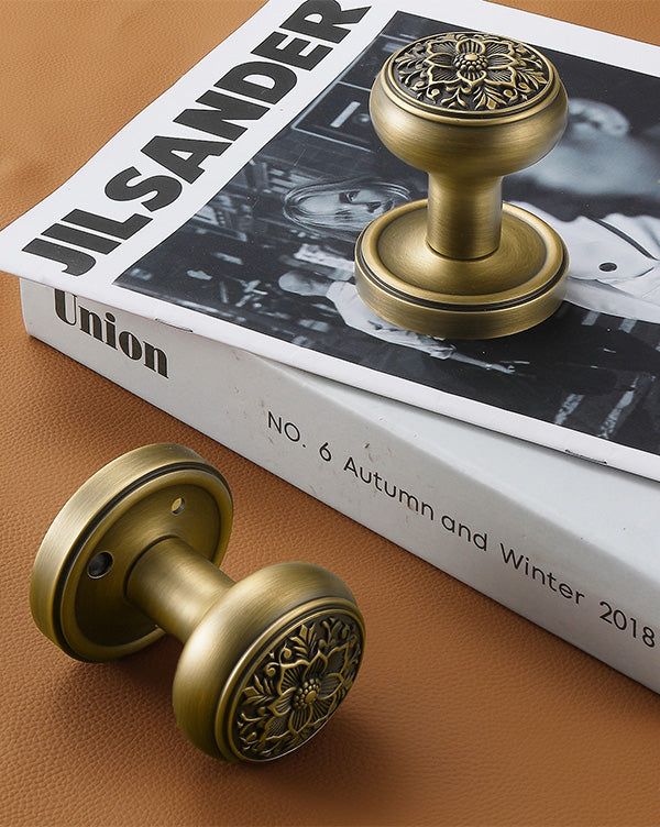 Pair of antique brass floral privacy door knobs displayed on magazine for vintage interior decor