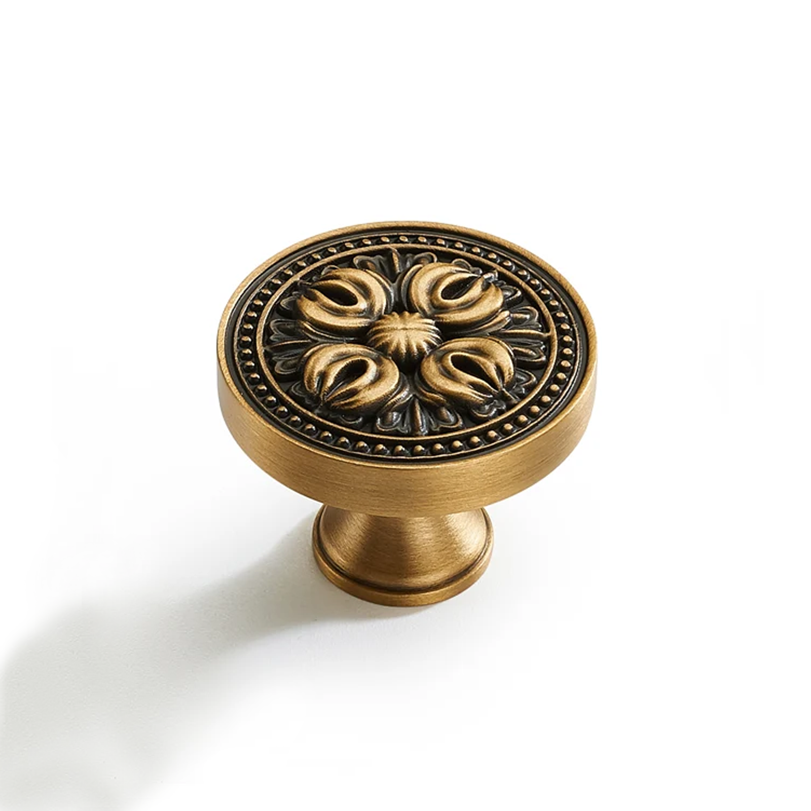 Flirabbit antique brass floral cabinet knob with sculpted four-petal relief isolated on white background